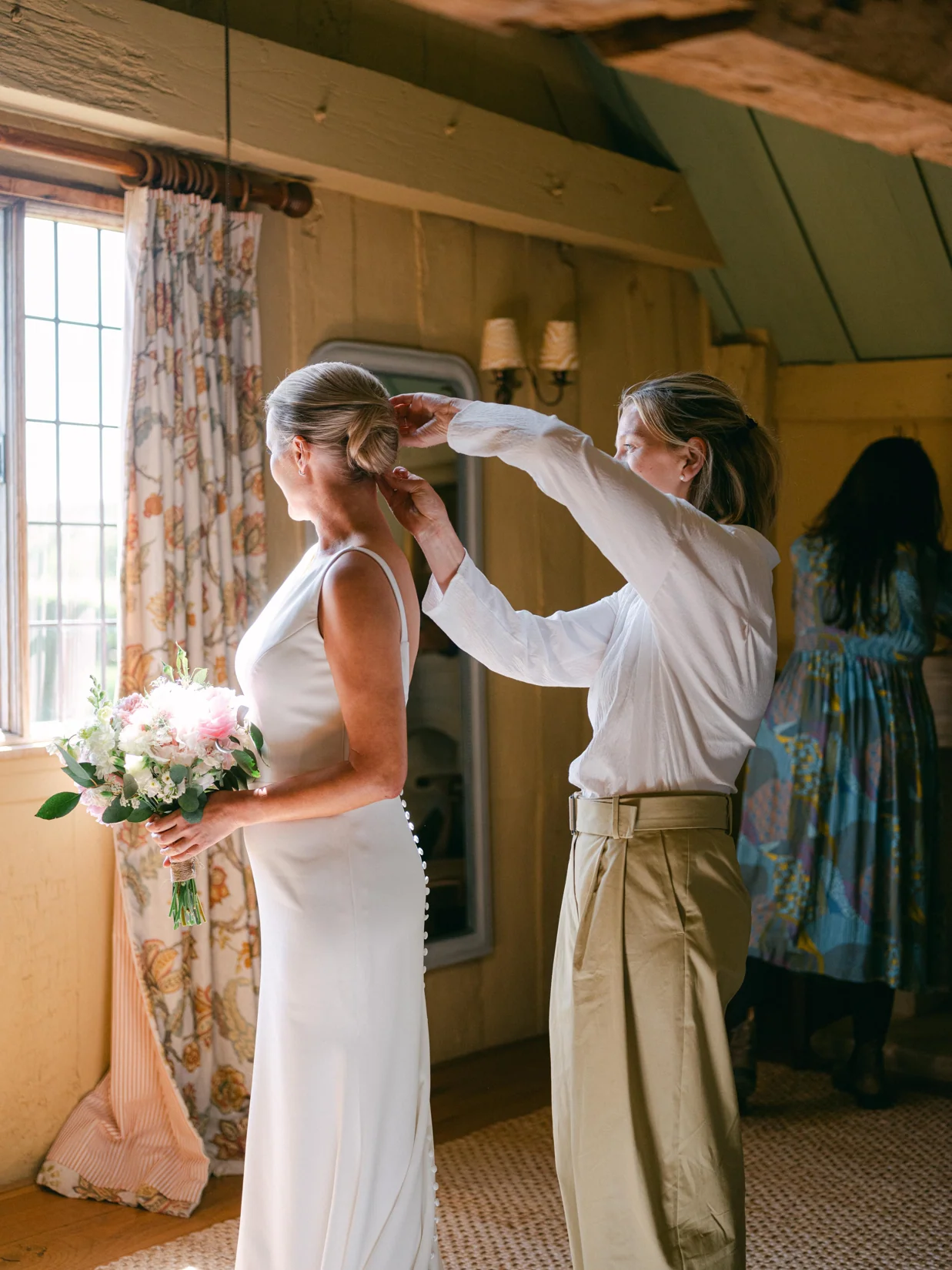 Charlotte Parker completing a bride's hairstyle in the soft light of her wedding morning